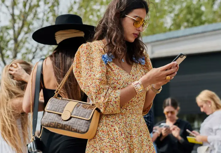 Kobieta w kwiecistej sukience i okularach przeciwsłonecznych, z torebką Fendi, uosabia styl boho moda.